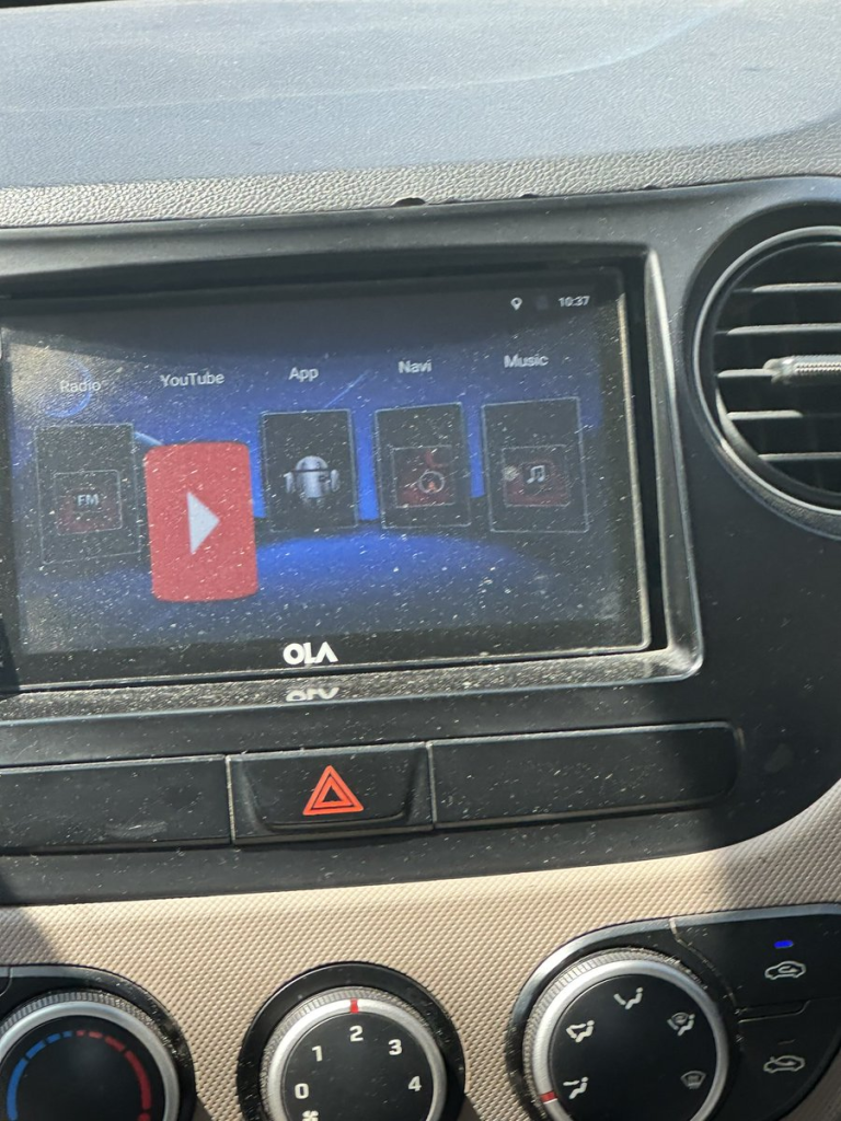 A close-up view of a car infotainment system displaying radio, music, navigation, and media applications on a digital dashboard screen. The image represents modern in-car radio and audio experiences connected to radio advertising in India through commuter-focused entertainment and media consumption.