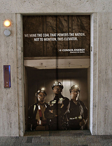 A creative elevator branding campaign transforms elevator doors into a powerful coal mining themed advertisement featuring miners and the message “We mine the coal that powers the nation. Not to mention, this elevator.” The immersive indoor advertising setup uses elevator door wraps and storytelling visuals to create a memorable brand experience in commercial spaces.
