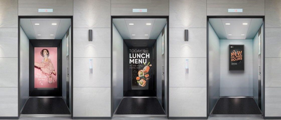 Elevator interior branding displaying full-height digital advertisements on the back walls of multiple elevators, showcasing fashion, restaurant, and promotional campaigns in a modern commercial building.
