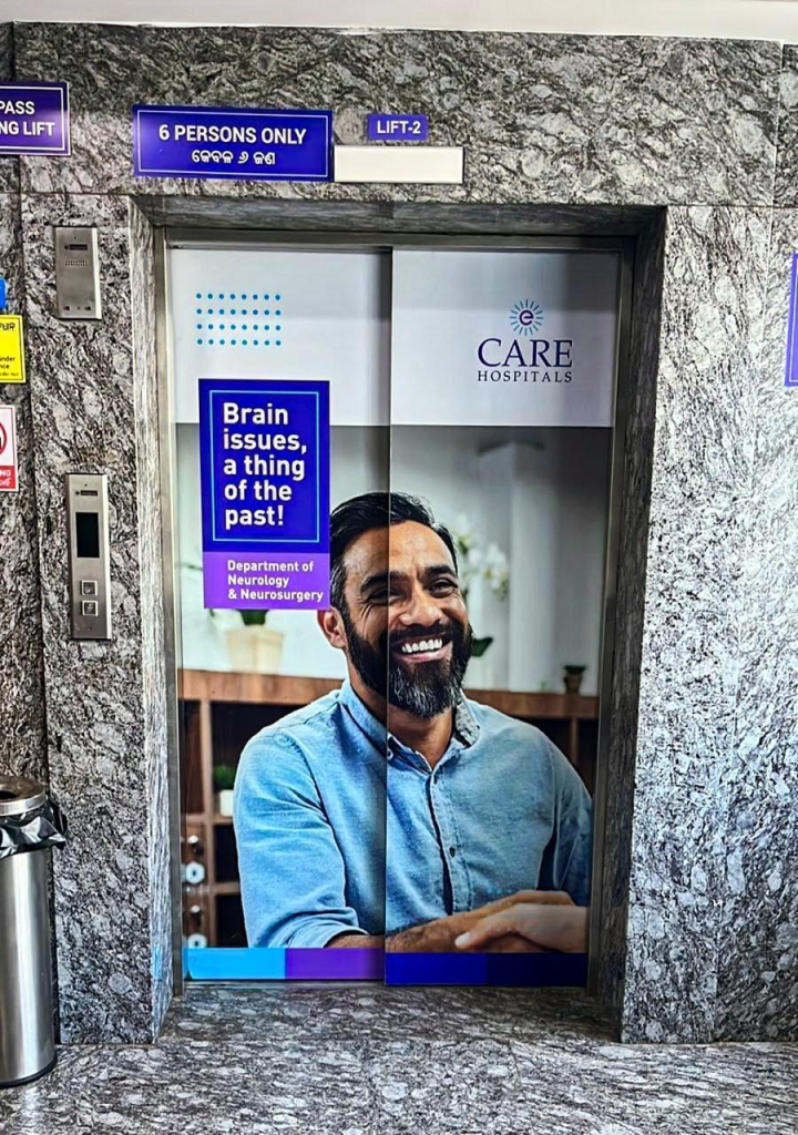 Elevator door branding for Care Hospitals featuring a smiling patient and a neurology campaign message, promoting neurological care and neurosurgery services within a hospital environment.