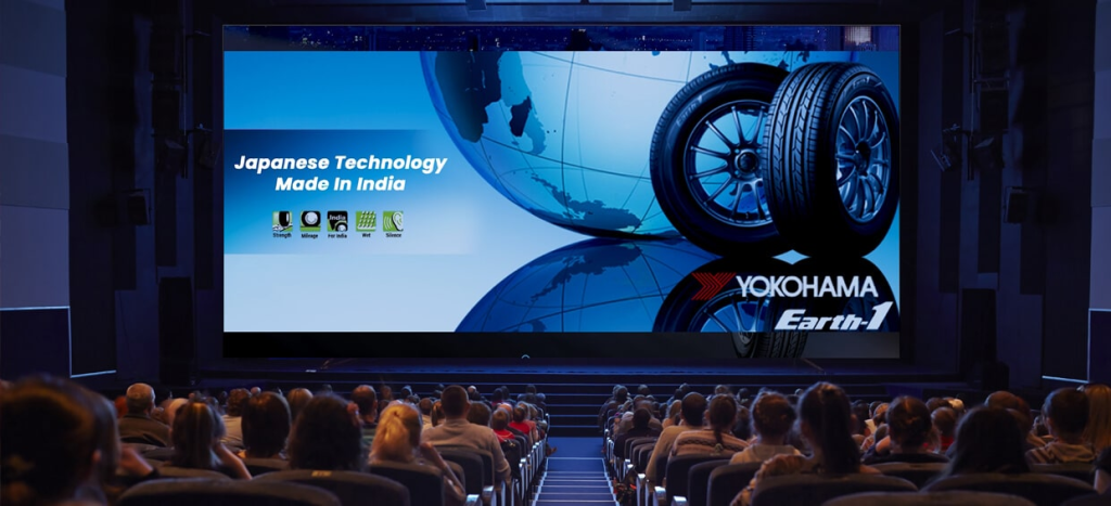 A Yokohama tyre advertisement is displayed on a large cinema screen inside a packed movie theatre. Featuring product visuals and brand messaging, the ad leverages the immersive cinema environment to capture audience attention and deliver high impact brand visibility before the film begins.